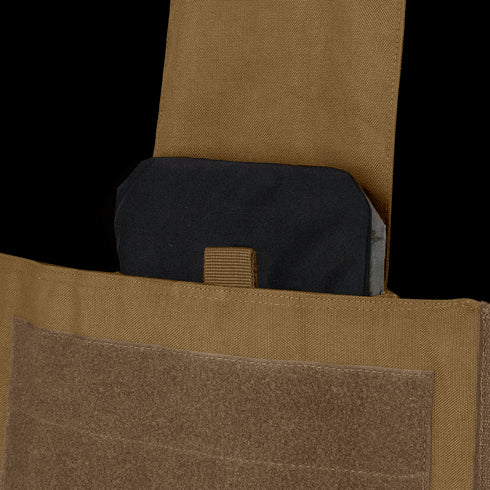 A close-up of a black ballistic plate partially inserted into the front pocket of a Condor Modular Operator Plate Carrier Gen II with a tan Velcro flap.